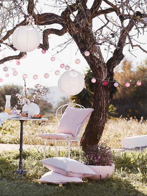 Udekorowany ogród za pomocą lampionów, poduszek oraz girlandy cotton balls