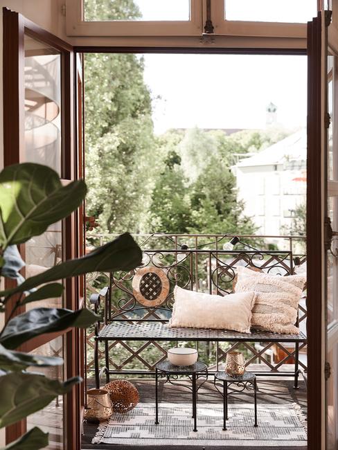 Taras z metalową ławką oraz poduszkami urządzony w stylu boho