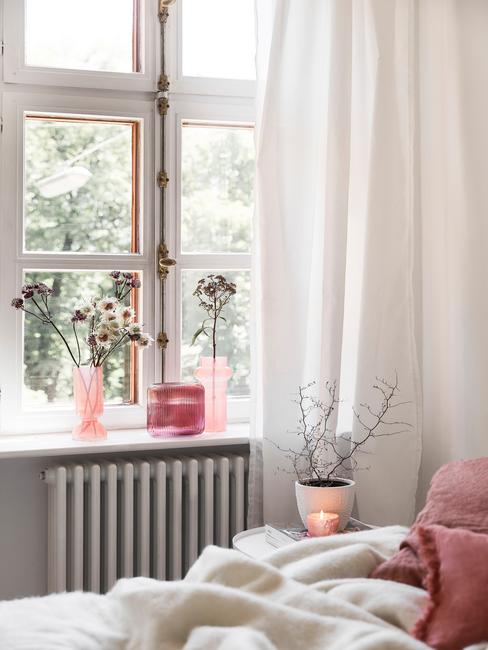 Biała sypialnia z dodatkami w postaci wazonów oraz koca w kolorze millenial pink