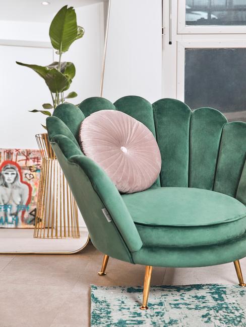 Fragment salonu z fotelem muszelką w kolorze sage green oraz poduszką w kolorze millenial pink
