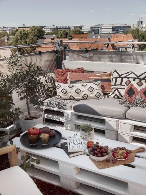 Balkon w bloku z meblami z palet i wzorzystymi poduszkami