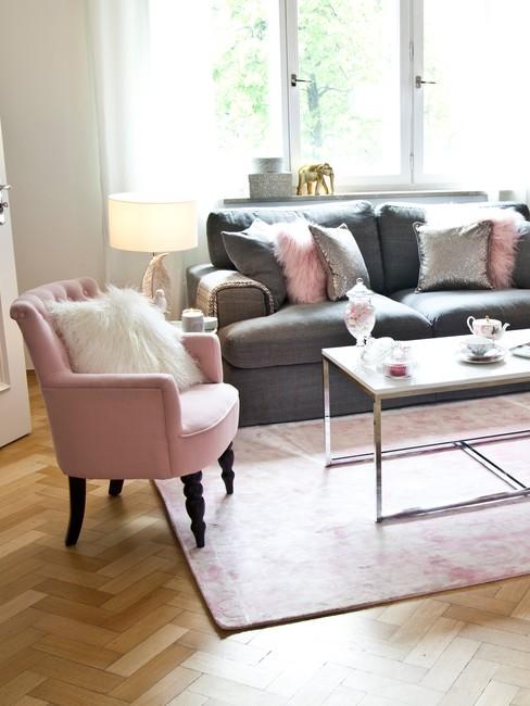 Jasny salon w stylu shabby chic z szarą kanapą, różowym fotelem oraz białym stolikiem kawowym