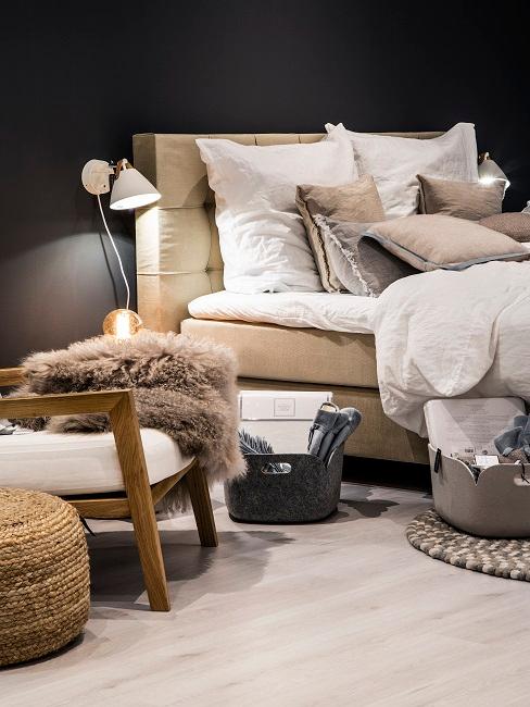 Bett in Beige vor schwarzer Wand mit Wandleuchten