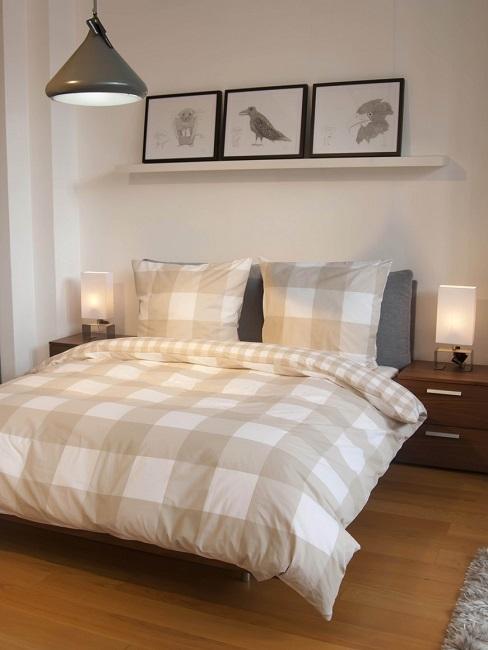 Schlafzimmer mit Wandbildern über Doppelbett mit karierter Bettdecke