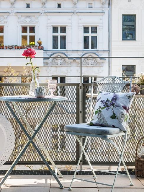 Gartenstuhl aus Metall neben Tisch auf Balkon