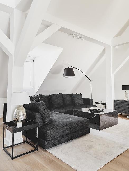 männerwohnung Ein dunkles Ecksofa mit schwarzem Couchtisch in Marmoroptik auf einem hellen Teppich in einer Männerwohnung