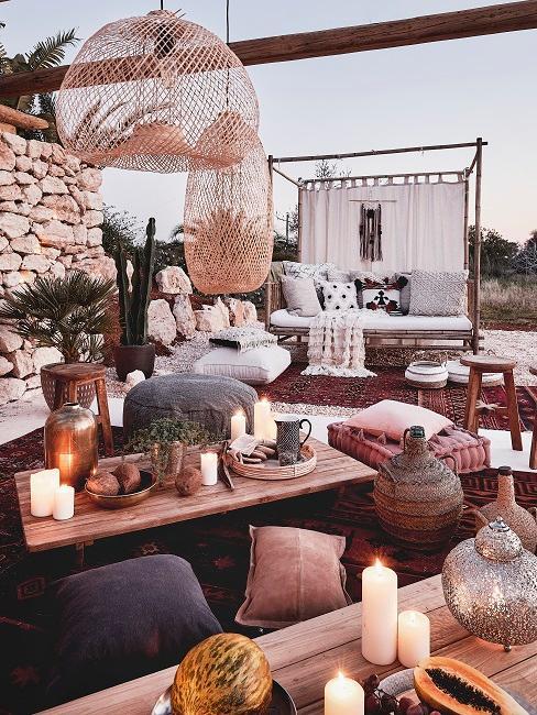 Coin oriental à l'extérieur avec bougies, coussins; poufs, déco en rotin et table en bois massif