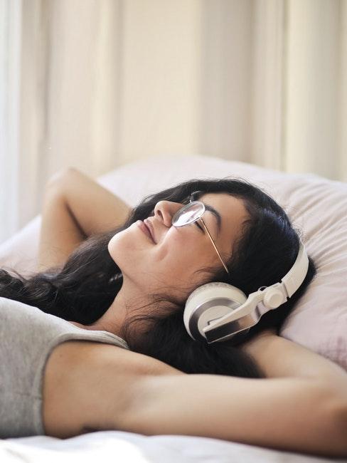 ragazza distesa aletto che ascolta audiolibri