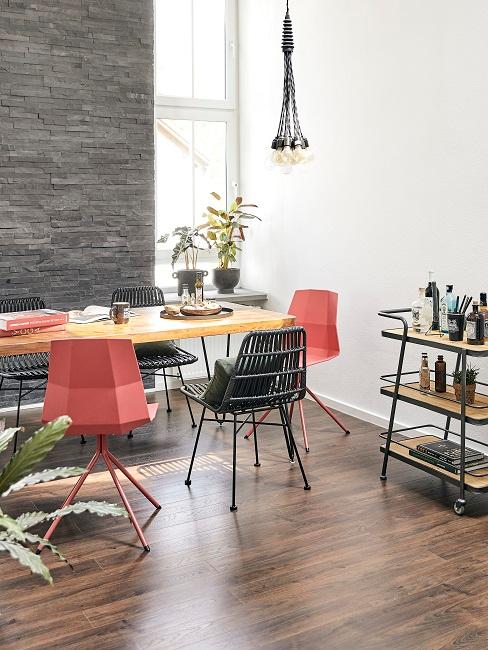 Esszimmer rustikal Esstisch aus Holz mit modernen Stühlen in verschiedenen Farben, daneben ein Servierwagen aus Holz