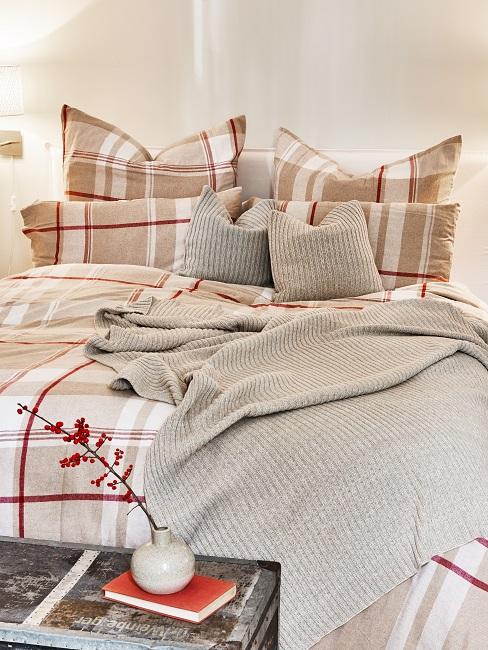 Doppelbett mit karierter Bettwäsche und zwei kleinen Extrakissen sowie einer Extradecke