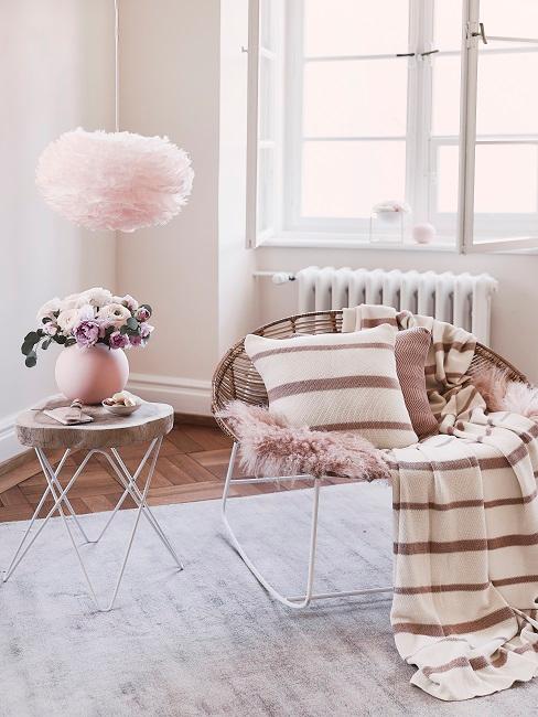 Lámpara de plumas Lámpara de plumas, mesa axiliar con jarrón rosa y sillón decorado con manta y cojín a rayas