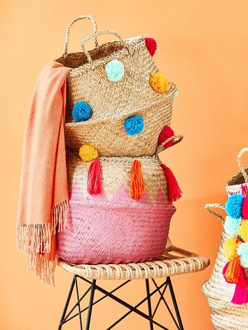 Hippie-Deko Bast-Körbe mit bunten Bommeln auf einem Stuhl und einer Decke in Neon Orange