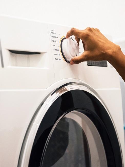 Wasmachine schoonmaken Wasmachine met vrouwelijke hand die aan de knop draait