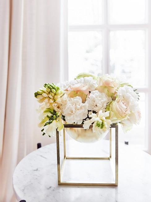 Weiße Rosen in einer goldenen Deko-Schale auf einem Tisch