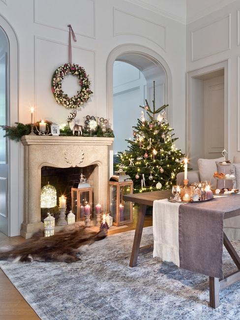 Wohnzimmer weihnachtlich dekorieren Gemütliches Wohnzimmer mit gedecktem Tisch auf eiem Teppich und Kamin, dazu viel Weihnachtsdeko wie ein Kranz und ein geschmückter Baum