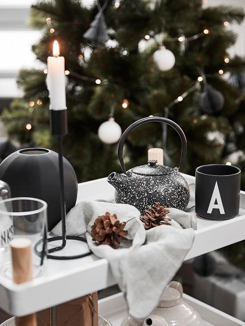 Tannenzapfen Deko Tablett vor einem Weihnachtsbaum mit einer Teekanne, einer Kerze, einer Tasse und Tannenzapfen als Deko