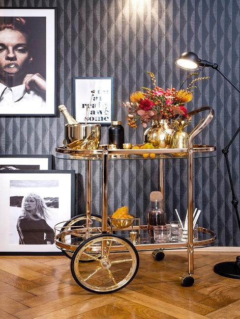 60er Style Barwagen vor einer Wand mit Retro Tapete und Bildern, darauf viel Deko und Barzubehör