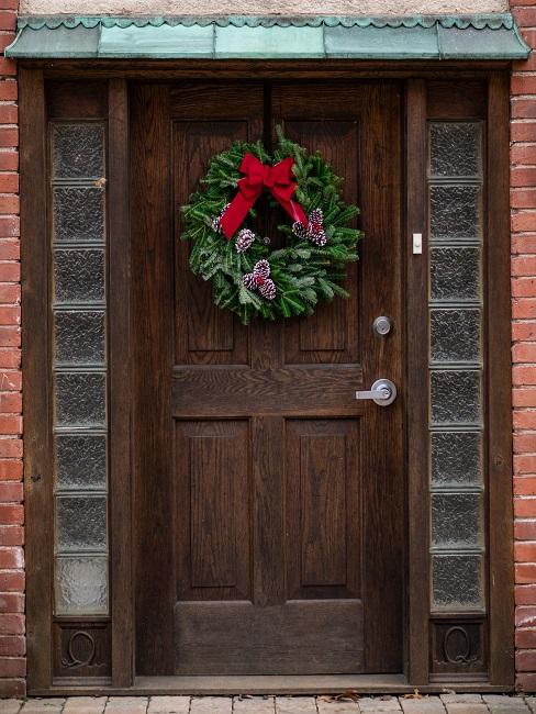 weihnachtsdeko draussen Haus von außen mit dunkler Holztüre, daran ein Weihnachtskranz als Deko für draußen