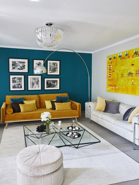 Wandfarbe Petrol im Wohnzimmer als Akzent an einer Wand mit gelbem Sofa und weißem Teppich