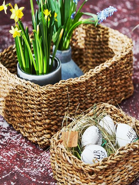 Körbe gefüllt mit Ostereiern und Blumentöpfen mit Narzissen