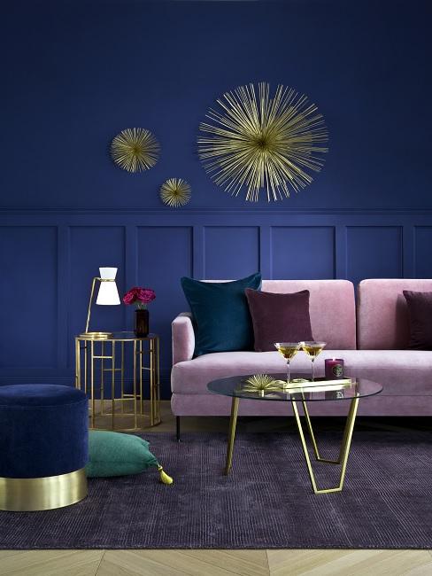 Dunkelblaue Wohnzimmerwand mit rosa Sofa und golderner Wanddeko