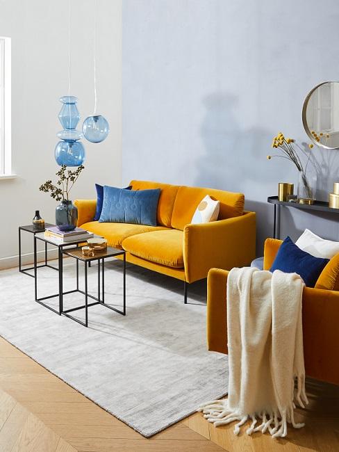 Hellblaue Wand in Wohnzimmer mit gelber Couch und blauen Kissen