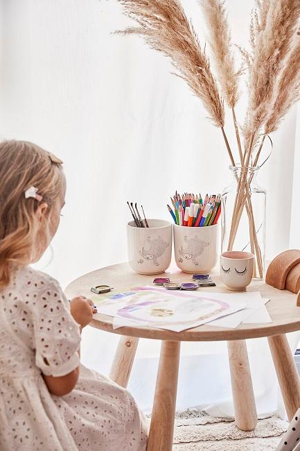 Mädchen sitzt an Tisch und malt
