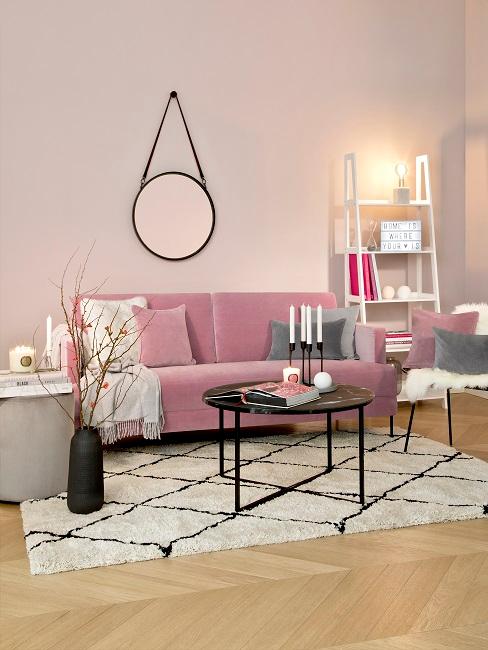 Wohnzimmer mit rosafarbenen Wänden, rosa Sofa, schwarz-weißer Teppich und Akzente in Schwarz
