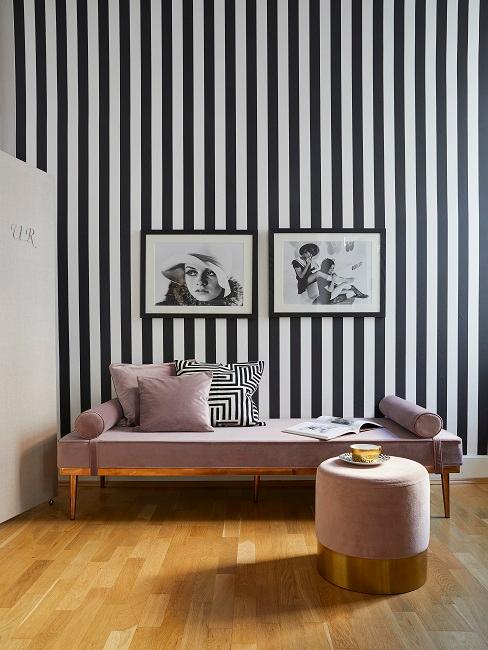 Schwarz-weiß gestreifte Wand mit Bildern und rosa Liege
