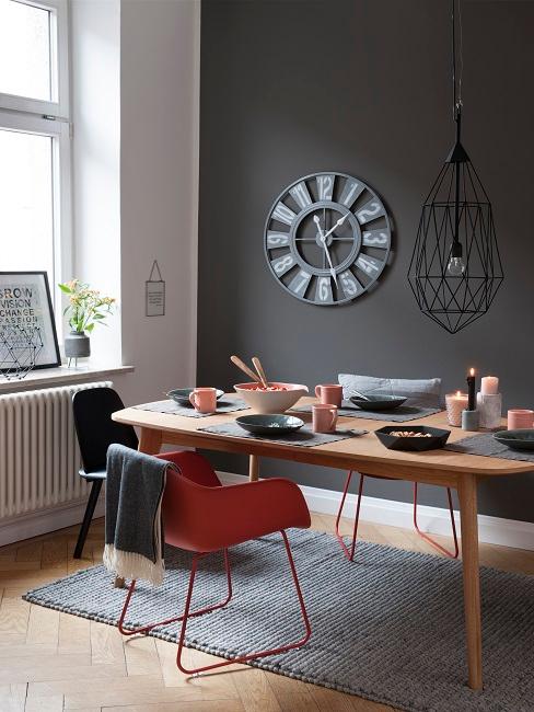 Schwarze Wand in Esszimmer it hellem Holztisch und roten Stühlen