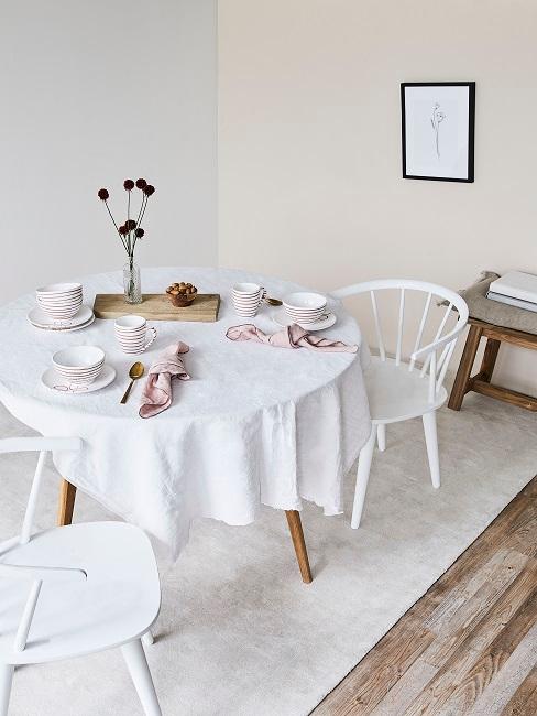 Weiße Wände im Esszimmer mit weißen Stühlen, Teppich und rundem Holztisch