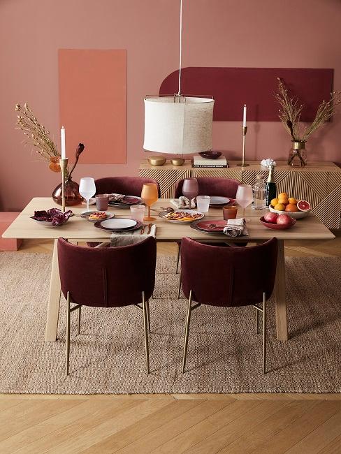 Wandfarbe Terracotta im Esszimmer mit Holztisch, Sideboard, Juteteppich und dunkelroten Stühlen