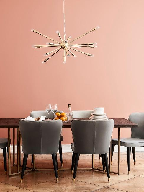 Esszimmer Wandfarbe in Koralle mit dunklem Holztisch, goldenen Pendelleuchte und grauen Samtstühlen