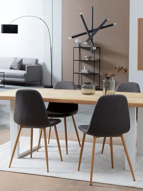 Wohn-Esszimmer mit beigefarbener Wand, hellem Holztisch, dunklen Stühlen und weißen Teppich