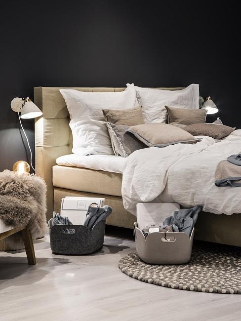 Schwarze Wand im Schlafzimmer mit beigefarbenem Bett, weißer Bettwäsche und Leuchten
