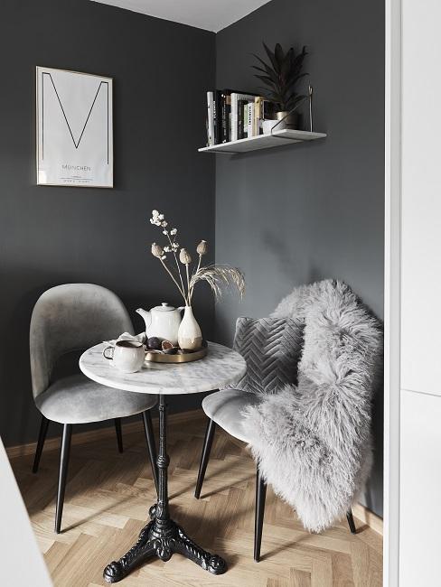 Dunkle Wandfarbe Grau mit hellgrauen Sesseln, kleiner Marmortisch und Lammfell