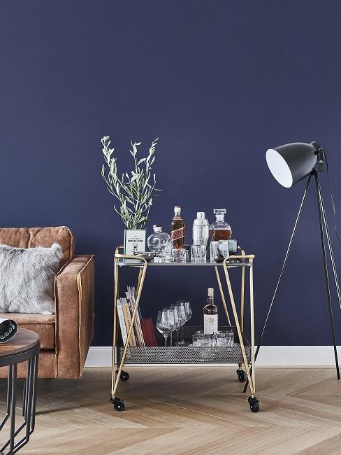 Dunkle Wandfarbe Blau mit braunem Ledersofa, schwarzer Stehlampe und silbernen Servierwagen