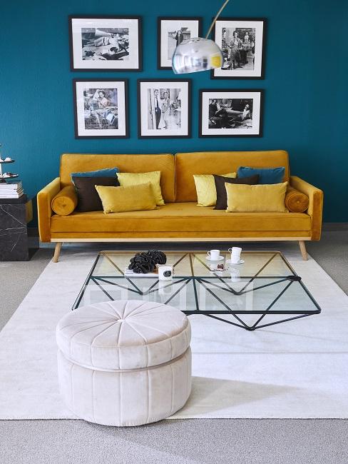 Petrolfarbene Wand im Wohnzimmer mit gelbem Sofa, weißem Teppich und Pouf