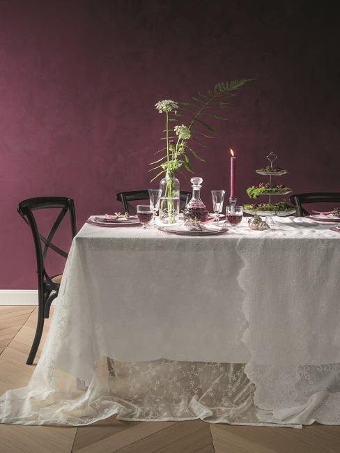 Dunkle Wandfarbe Aubergine im Esszimmer mit schwarzen Stühlen und Tisch mit weißer Tischdecke