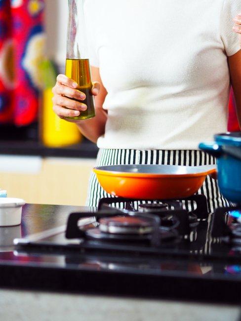Frituurpan schoonmaken Vrouw staat met olie voor een pan