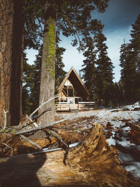 Houten huis met puntdak in het bos met een kleine laag sneeuw op de grond