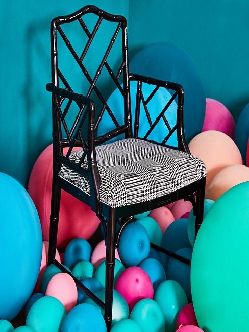 Hausparty Stuhl inmitten lauter bunter Luftballons
