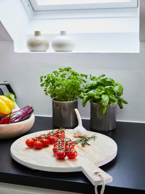 cocina-encimera Encimera de la cocina negra con base de madera y tomates en rama