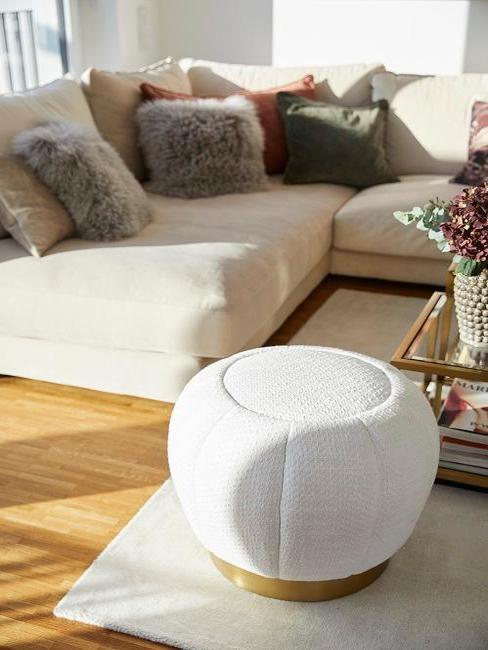 tendencias-decoracion-2020 Salón con pouf blanco en primer plano y al fondo un sofá esquinero