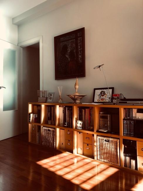 muebles-a-medida-banner Salón con cómoda alargada compuesta de cuadrados de madera con libros y cajas