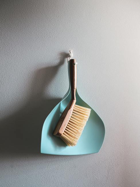 limpieza del hogar en profundidad Escoba y recogedor de mano colgados en la pared