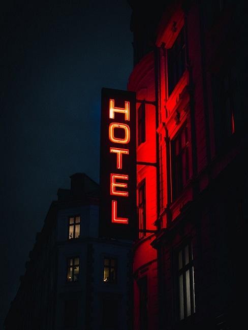 Hoteleinrichtung Leuchtschrift "Hotel" auf einem Schild nachts an einem Haus