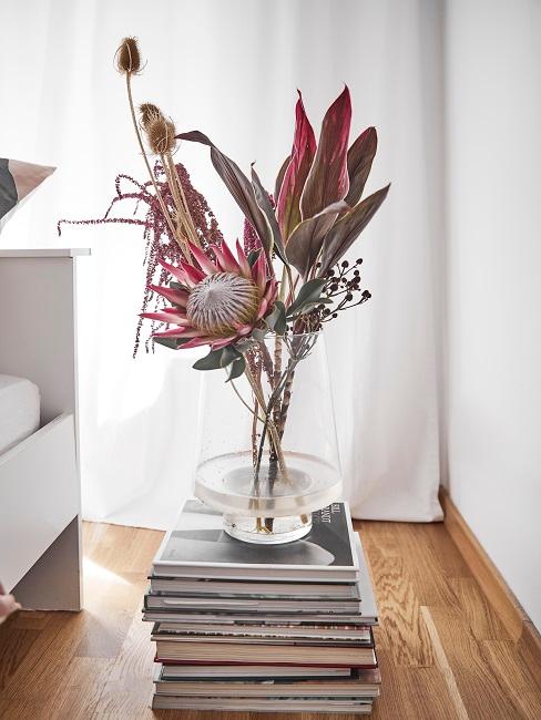 Vase mit Blumen auf Bücherstapel