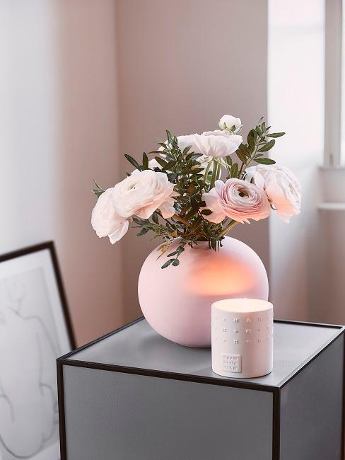 Runde rosa Vase mit Rosen neben einer Duftkerze