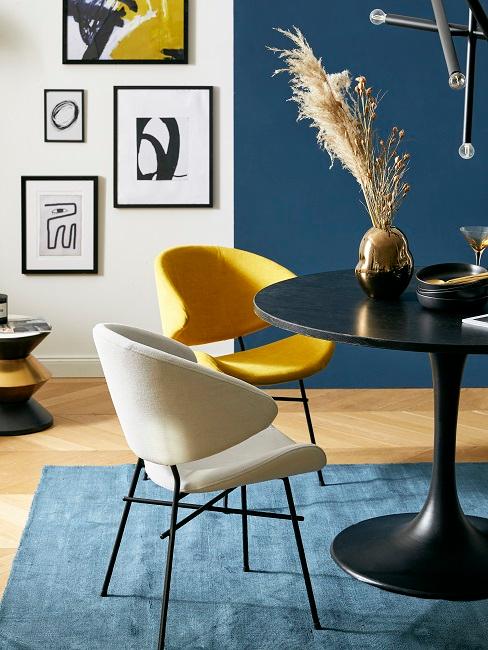 Gelber Stuhl in blauem Esszimmer mit Wandbildern und schwarzem Tisch